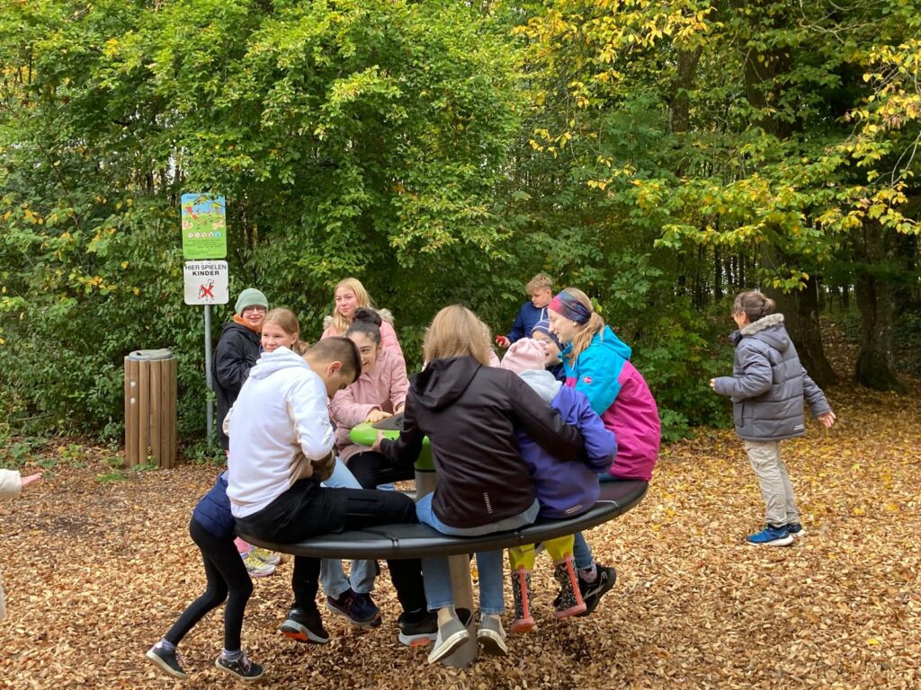 SuS von BGB und AWS siten gemeinsam auf einem Drehkarussel auf dem SPielplatz