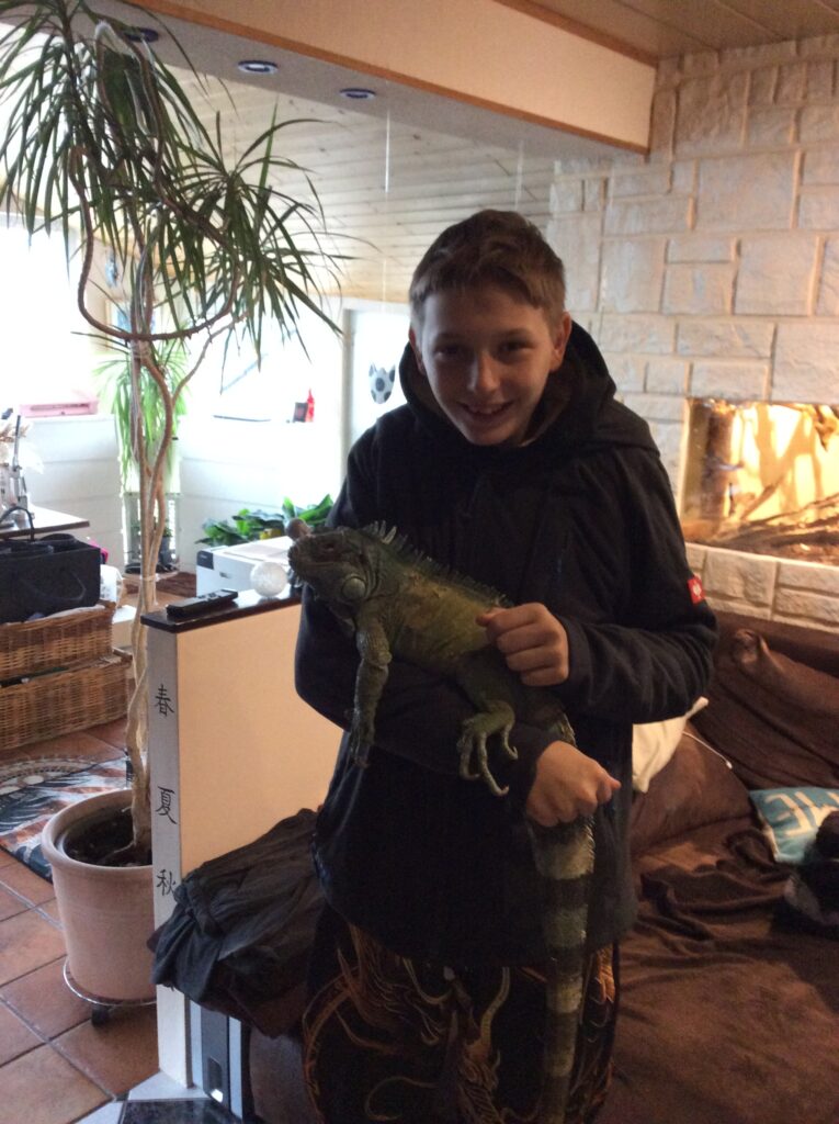 ein Schüler hat einen Leguan auf dem Arm