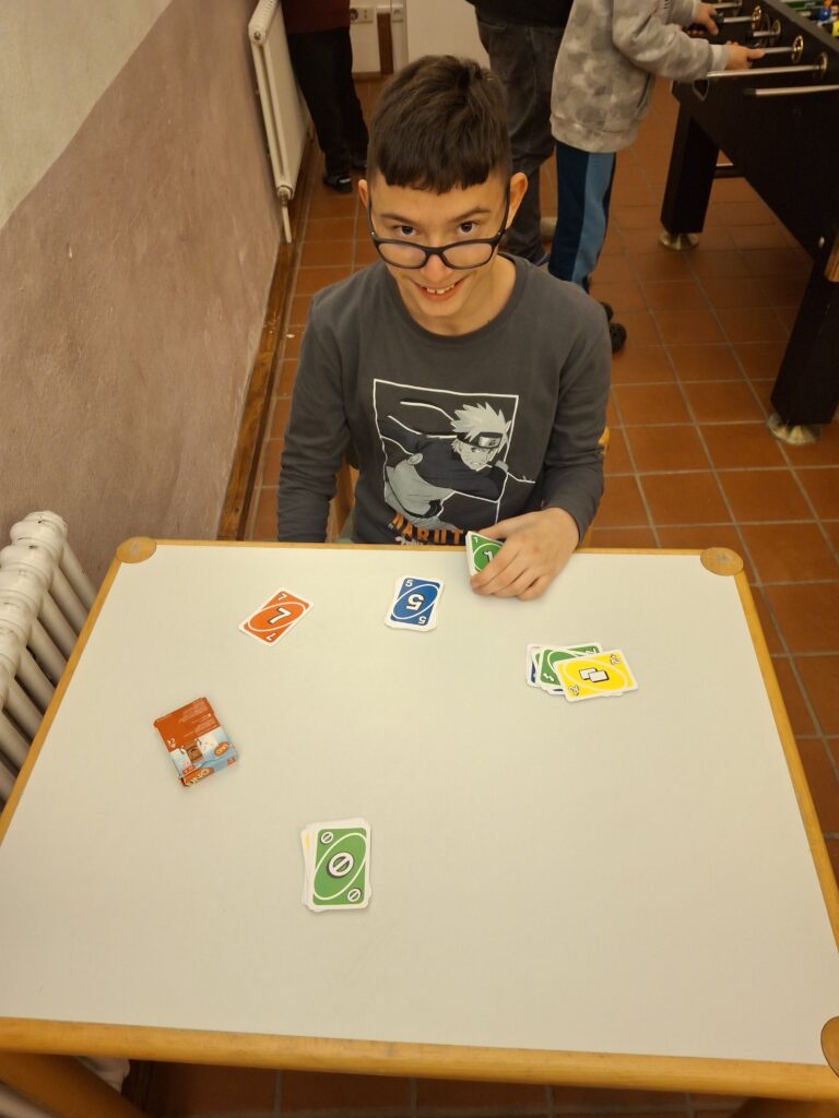 Ein Schüler sitzt mit Uno Karten an einem Tisch