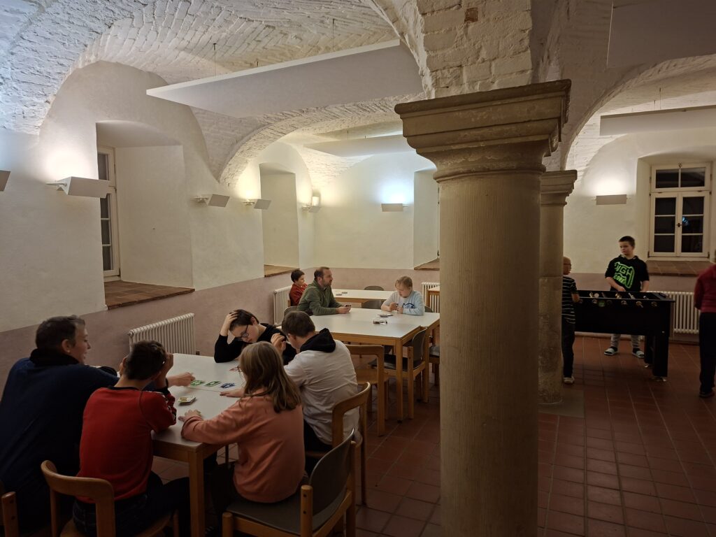 SchülerInnen sitzen um Tische un spielen Gesellschaftsspiele