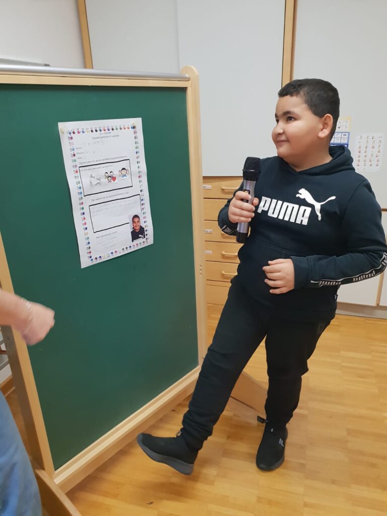 Ein Schüler stellt sich mit seinem Plakat zur Schülersprecherwahl vor