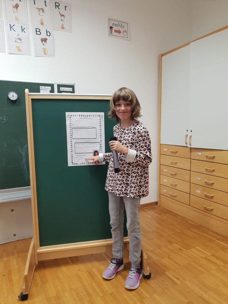 Eine Schülerin stellt sich mit seinem Plakat zur Schülersprecherwahl vor