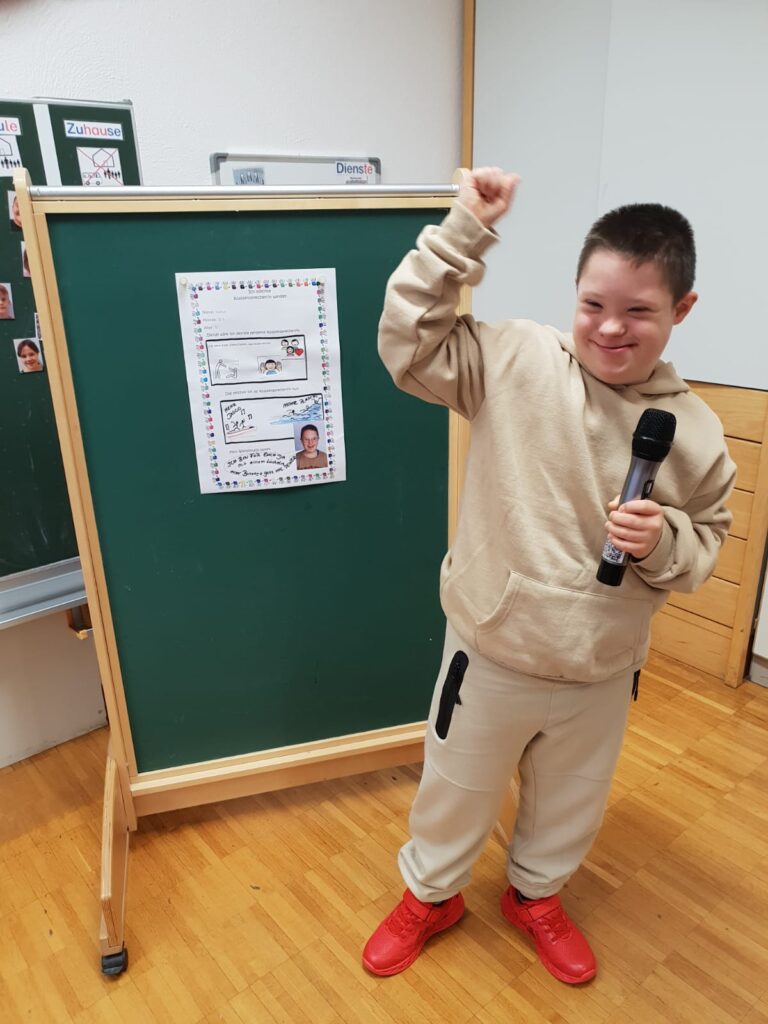 Ein Schüler stellt sich mit seinem Plakat zur Schülersprecherwahl vor