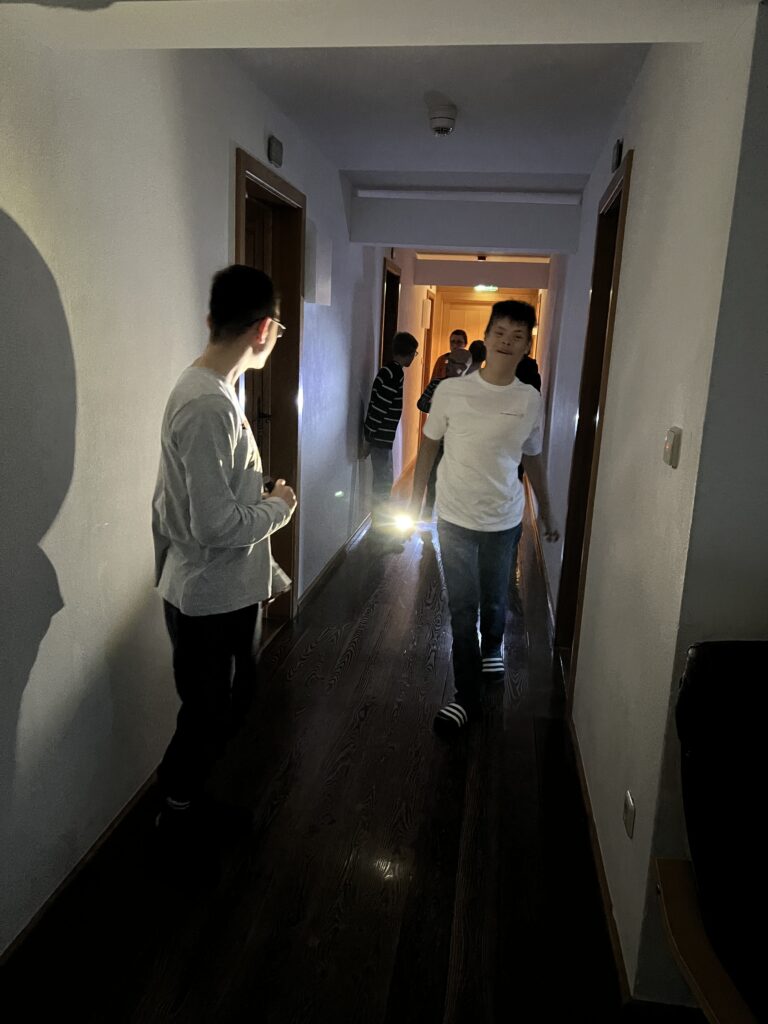 Schüler testen ihre Taschenlampen im Gang der Unterkunft