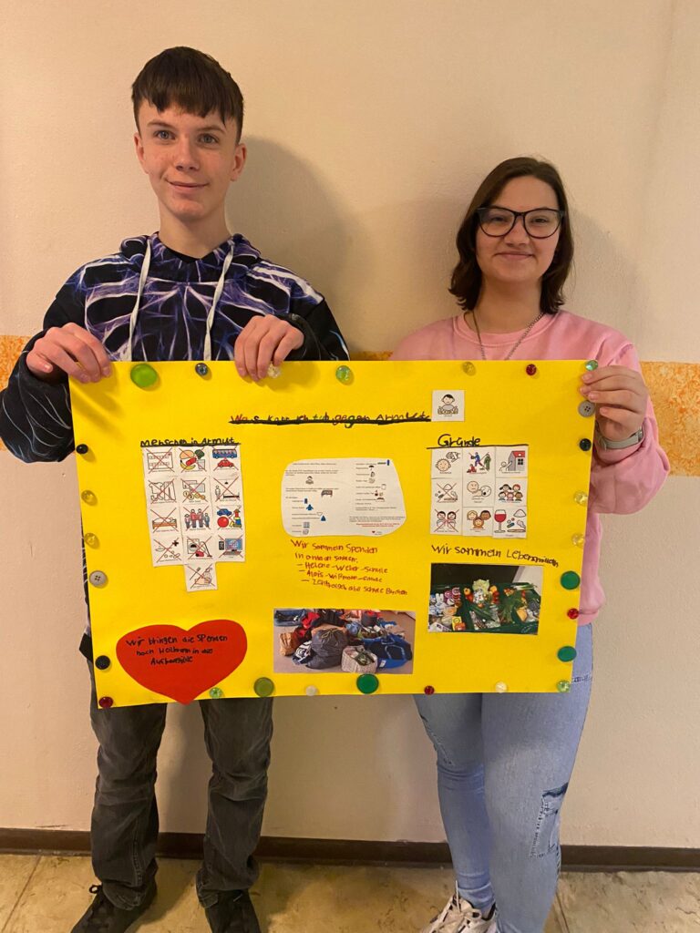 Eine Schülerin und ein Schüler zeigen ihr Plakat zum Thema Armut