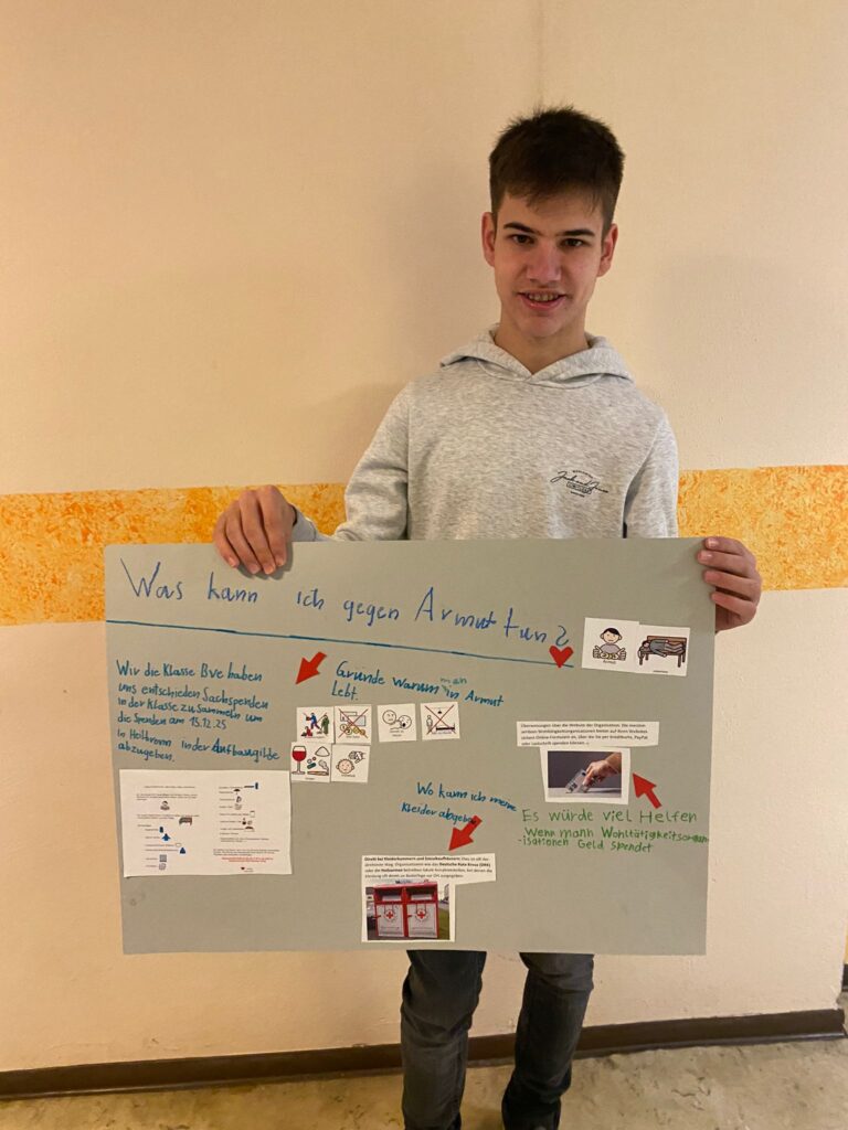 Ein Schüler zeigt sein Plakat zum Thema Armut
