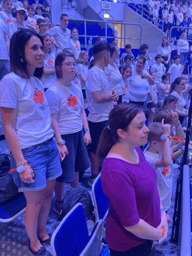 SchülerInnen stehen mit ihren Lehrerinnen auf dem Rang und singen 