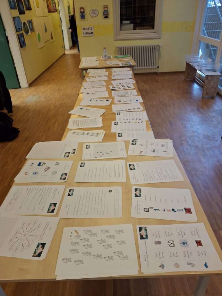 Tische voller Arbeitsblätter zum Projekt als Lerntheke im Schulgang aufgebaut