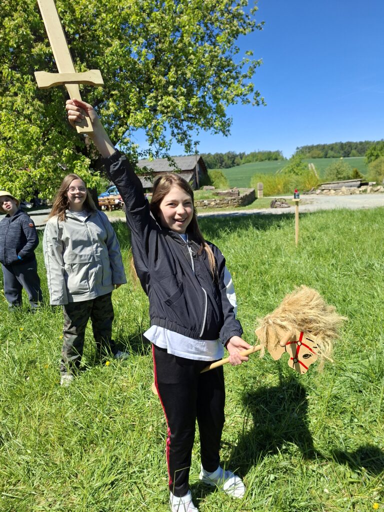 eine Schülerin reitet mit einem erhobenen Schwert auf einem Steckenpfer