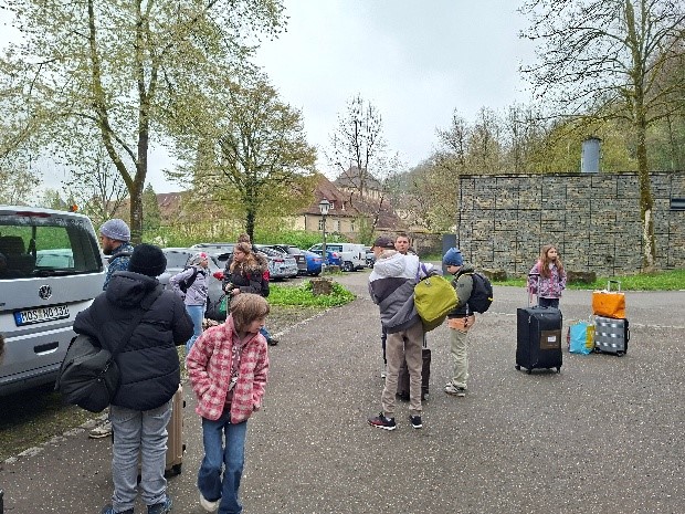 SchülerInnen mit Koffer stehen auf dem Parkplatz
