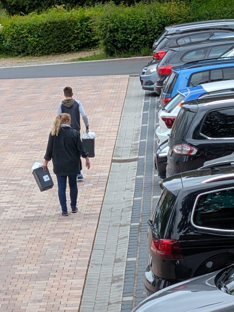 Ein Schüler und eine Lehrerin tragen Müll über den Parkplatz