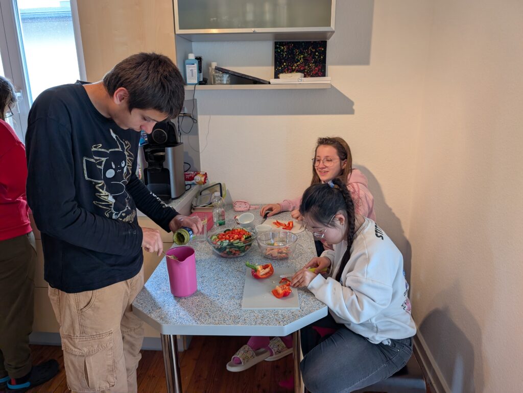 SuS sitzen am Tisch und schneiden Gemüse für das Abendessen